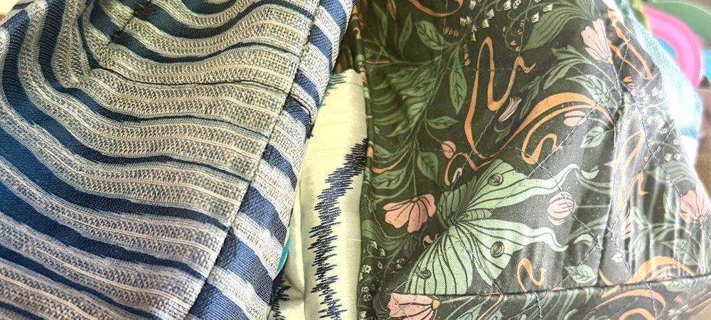 Mehrere fertige Taschen von LAMAI HANDMADE auf einer Kleiderstange in Wanphens Werkstatt